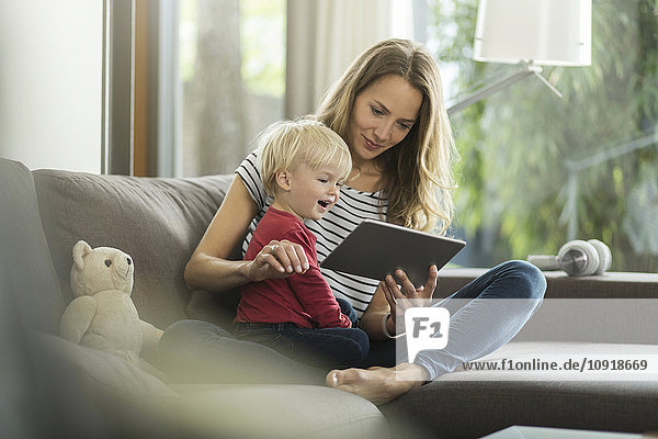 Mutter und Sohn auf Couch mit digitalem Tablett