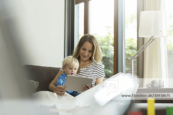 Mutter und Sohn auf Couch mit digitalem Tablett