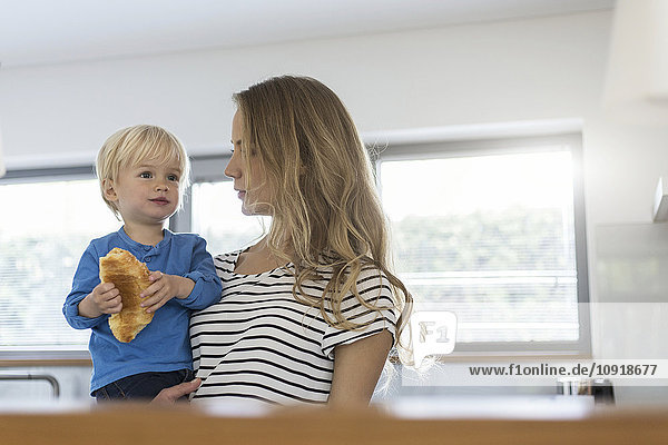 Mutter hält Sohn beim Croissant essen