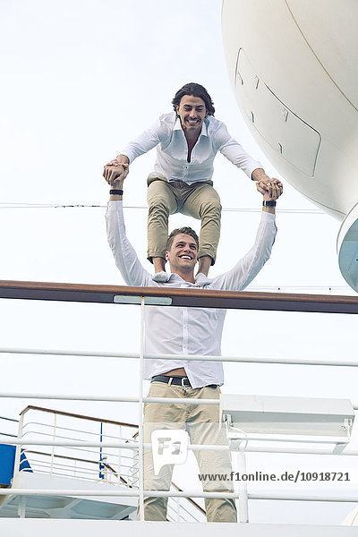 Zwei junge Männer  die sich auf einem Kreuzfahrtschiff herumtreiben und auf den Schultern balancieren.