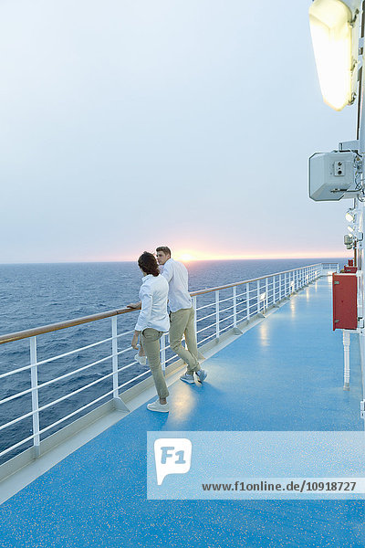 Junge Männer  die an Deck des Schiffes stehen und den Sonnenuntergang beobachten.