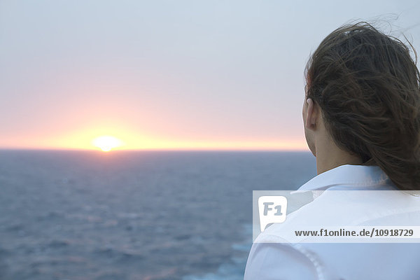 Junger Mann mit Blick auf den Sonnenuntergang über dem Meer
