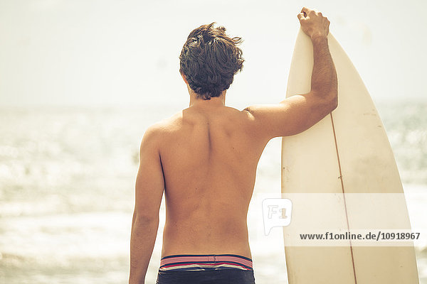 Rückansicht des jungen Mannes mit Surfbrett