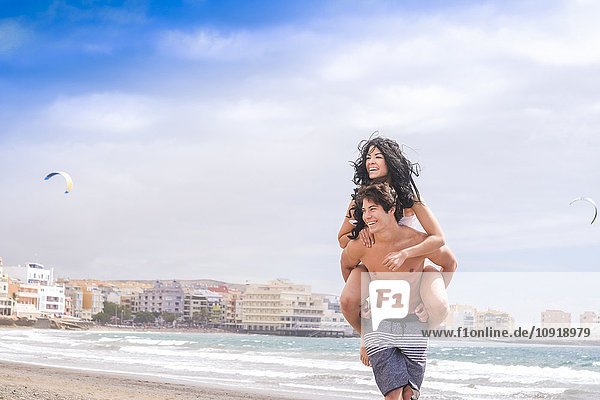 Spanien  Teneriffa  junger Mann  der seine Freundin huckepack fährt