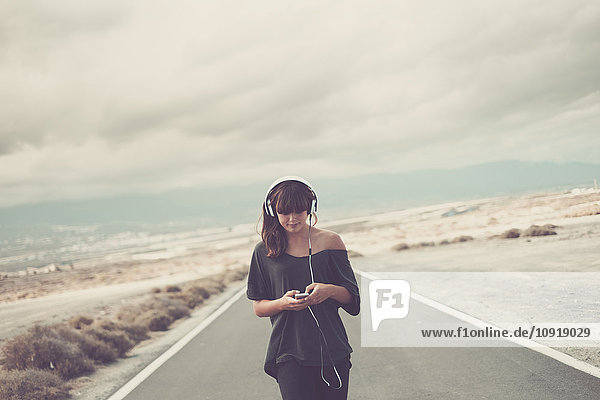 Young woman on the road listening music with headphones