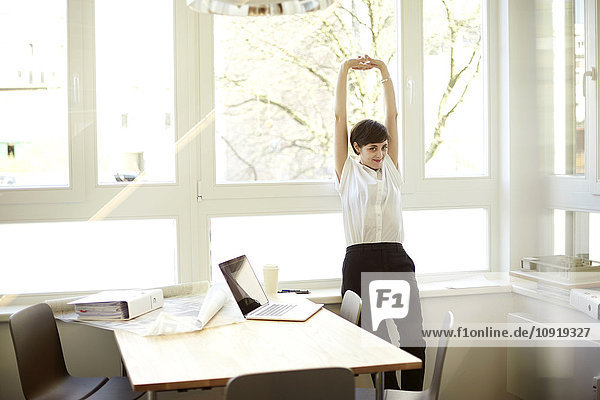 Woman doing stretching exercise in her office