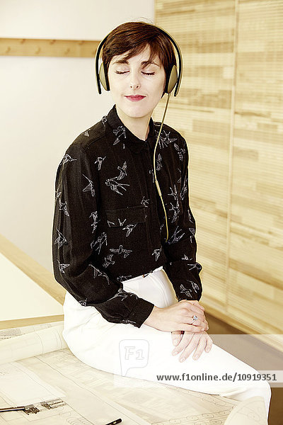 Frau beim Musikhören mit Kopfhörern im Büro