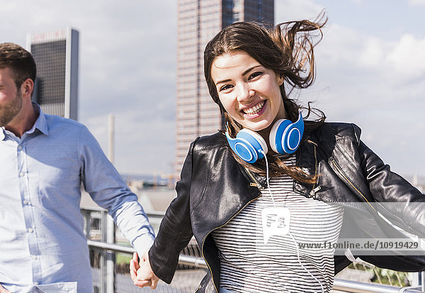 Happy young couple   woman jumping with headphones aroung neck