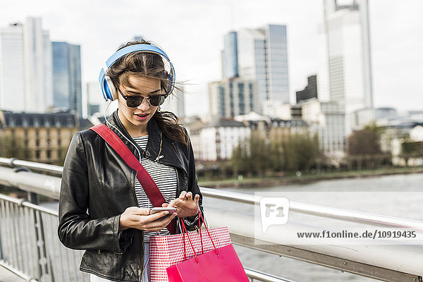 Junge Frau  die mit Kopfhörern in der Stadt spazieren geht.