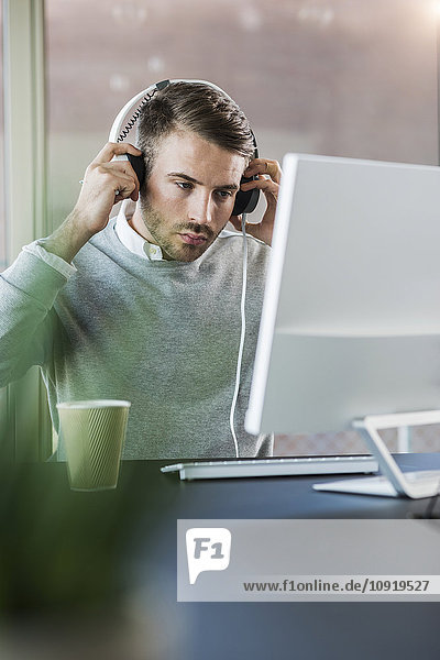Man at office desk wearing headphones