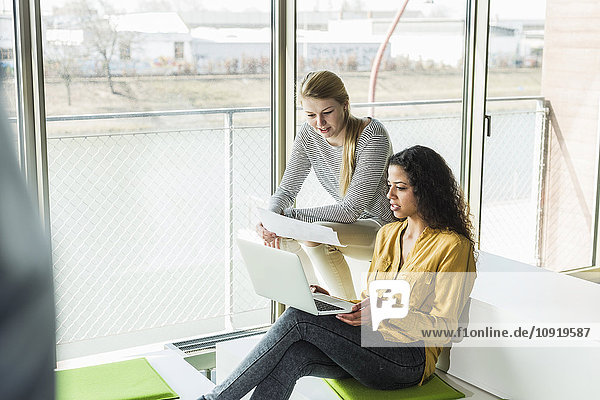 Two women in office with laptop and document
