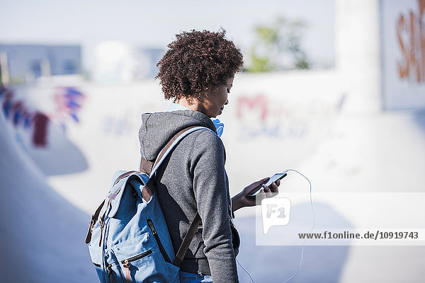 Junge Frau mit Rucksack und Handy im Freien