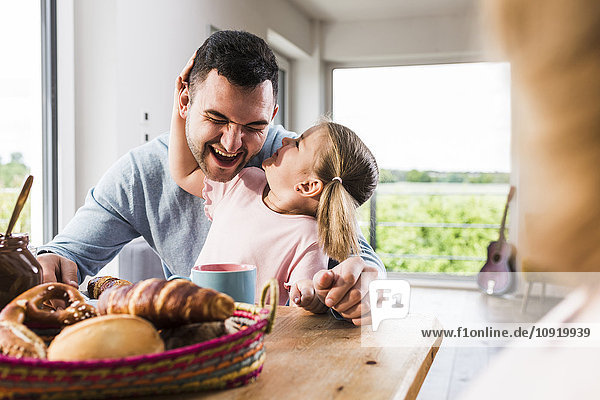 Playful daughter with father at breakfast table