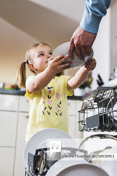 Daughter helping father clearing dishwasher