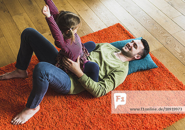 Playful father and daughter lying on carpet on the floor