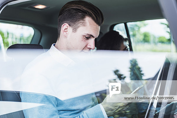 Junger Mann mit Handy und Frau im Auto