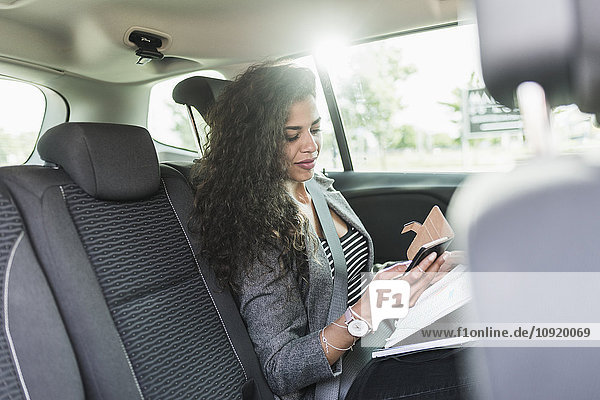 Young woman in car looking at cell phone