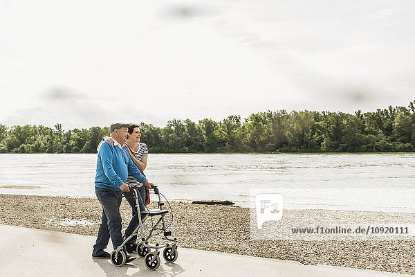 Ein älterer Mann  der mit seiner Tochter am Flussufer spazieren geht.