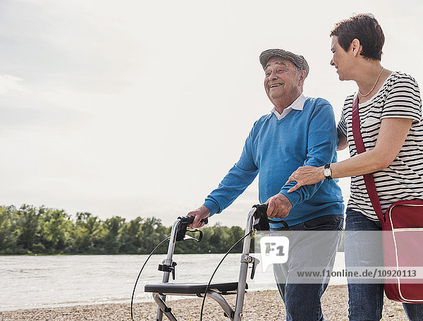 Ein älterer Mann  der mit seiner Tochter am Flussufer spazieren geht.