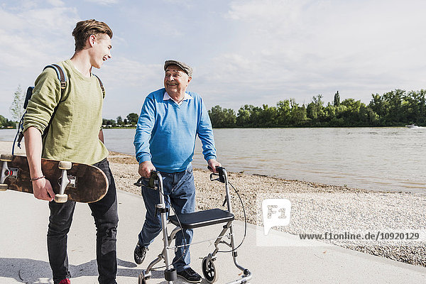 Grandfather and grandson strolling together at riverside