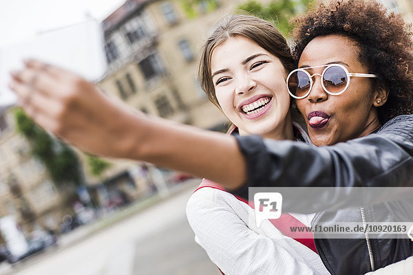 Portrait of two happy best friends taking selfie with smartphone