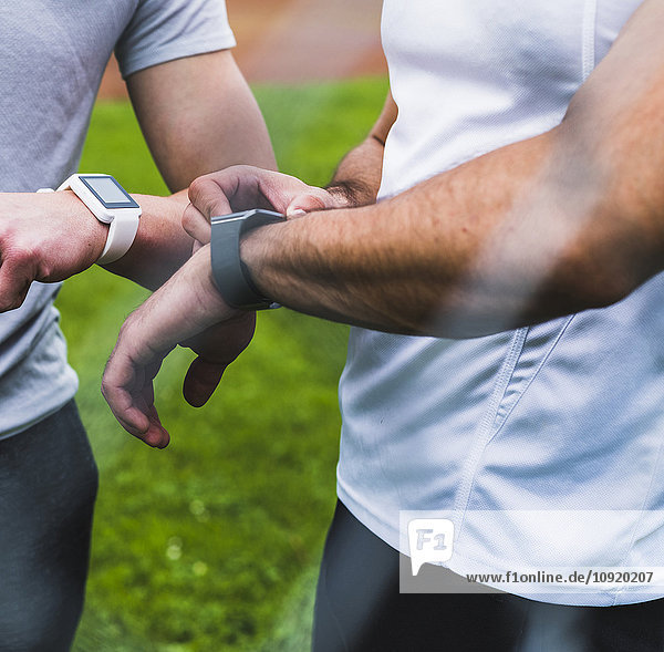Close-up of two athletes with smartwatches outdoors