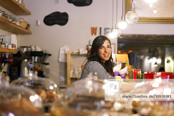Junge Frau arbeitet in ihrem eigenen kleinen Cafe.