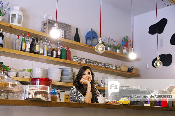 Junge Frau arbeitet in ihrem eigenen kleinen Cafe.