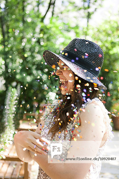 Enthusiastic young woman playing with confetti