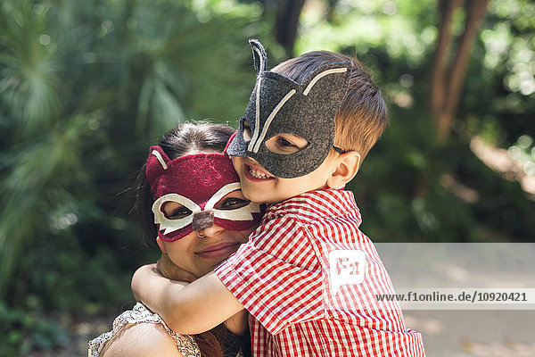 Mutter und kleiner Sohn mit Tiermasken beim Spielen im Park