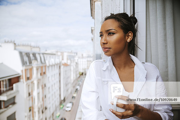 Frankreich  Paris  Porträt einer jungen Frau mit einer Tasse Kaffee in der Ferne
