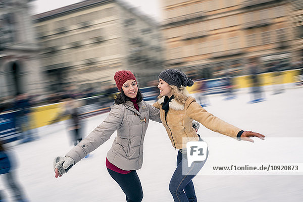 Two happy friends skating on outdoor ice rink