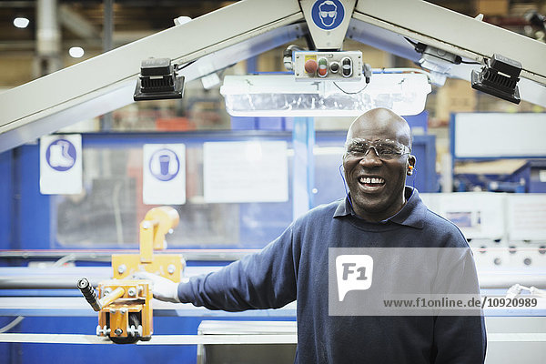 Portrait smiling worker at machine in steel factory