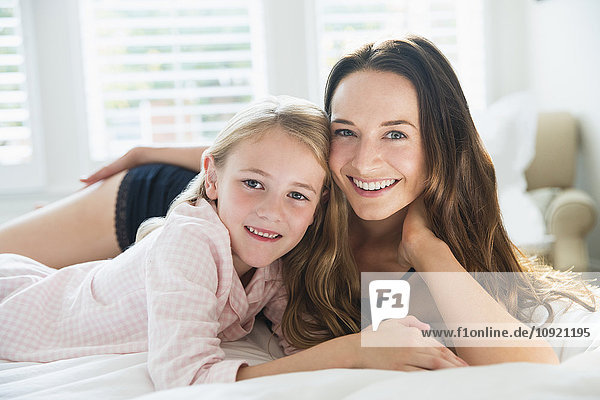 Portrait smiling mother and daughter laying on bed