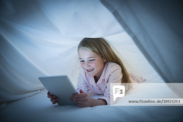 Lächelndes Mädchen mit digitalem Tablett unter dem Blatt