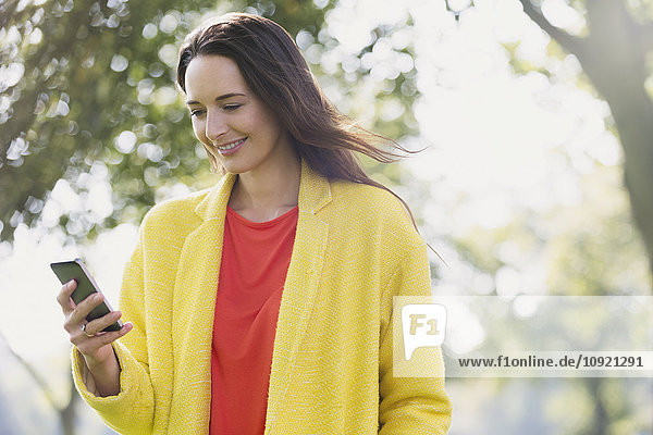 Lächelnde Frau mit Handy im Park