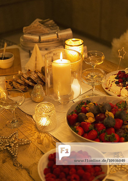 Essen und Dekorationen auf dem Weihnachtstisch bei Kerzenschein