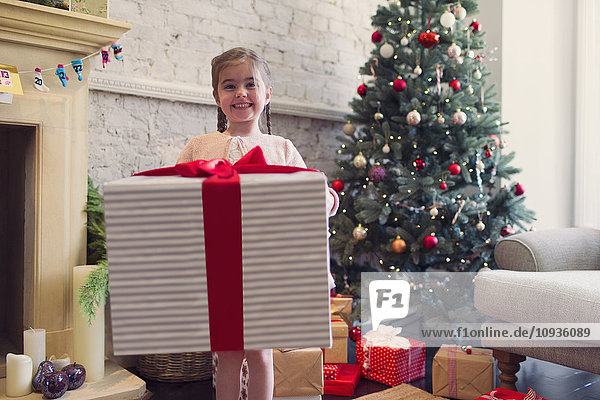 Portrait begeistertes Mädchen mit großem Weihnachtsgeschenk
