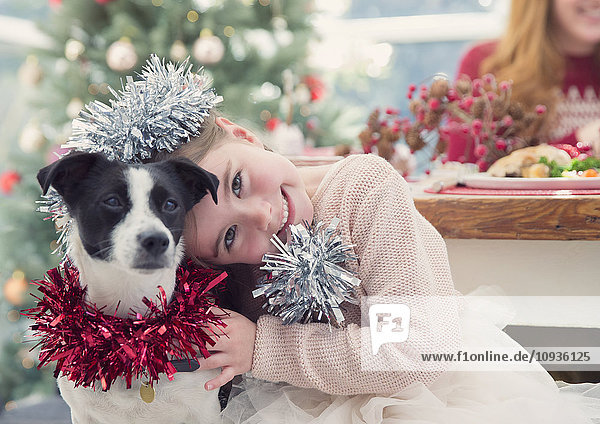 Portrait lächelndes Mädchen umarmender Hund mit Weihnachtsdekoration