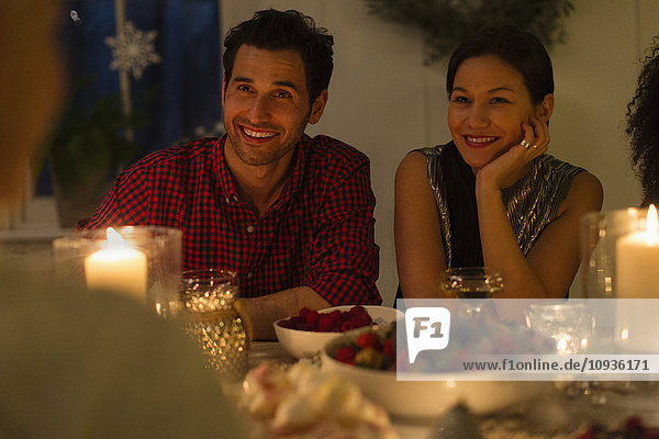 Lächelndes Paar beim Weihnachtsessen bei Kerzenschein