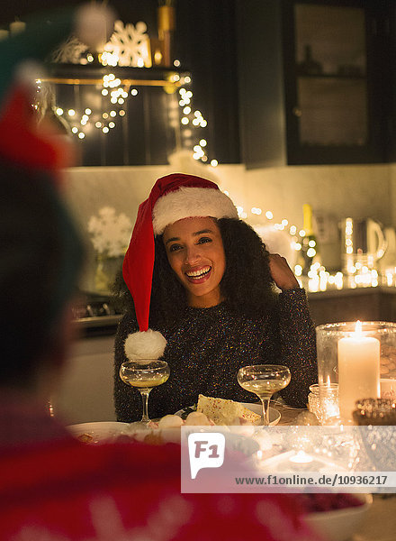 Lächelnde Frau mit Weihnachtsmütze bei Kerzenschein Weihnachtsfeier