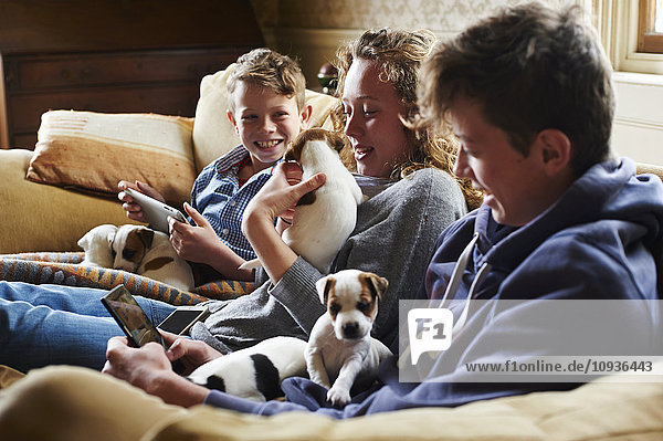 Brothers and sisters holding puppies on sofa