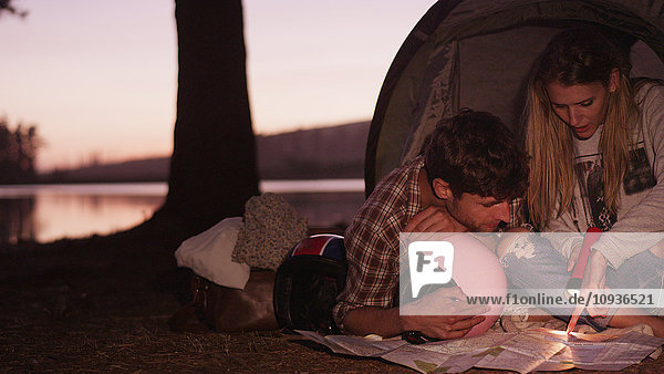 Junges Paar betrachtet Karten im Campingzelt