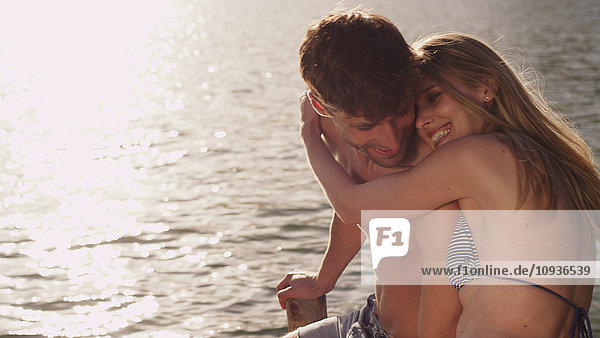 Zärtliches junges Paar  das sich am Seeufer umarmt