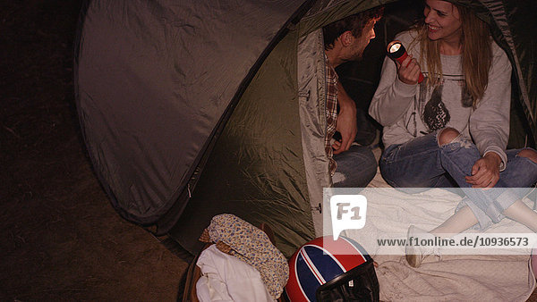 Junges Paar mit Taschenlampe im Campingzelt