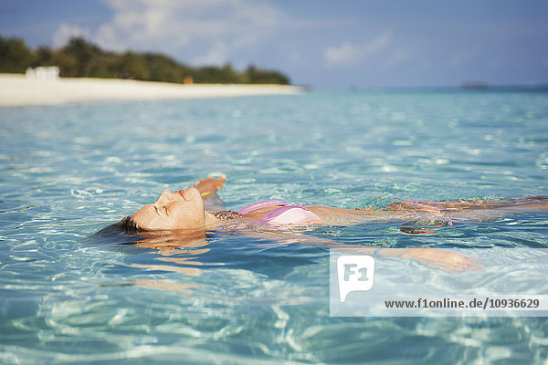 Gelassene Frau schwimmt im tropischen Ozean
