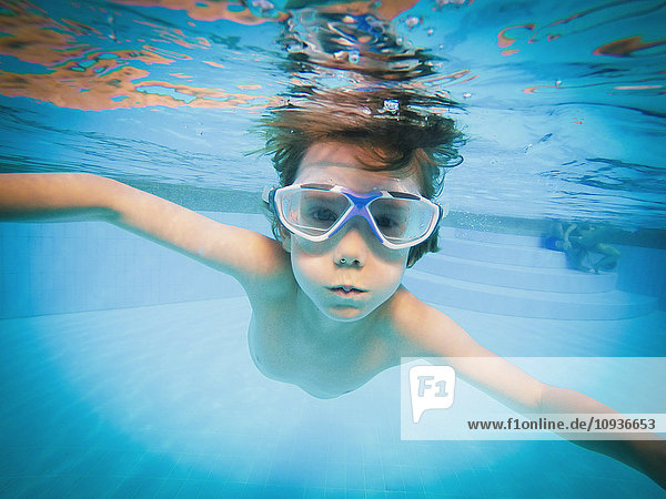 Porträt eines Jungen  der im Schwimmbad unter Wasser schwimmt