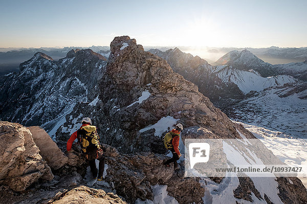 Two mountaineers climbing on mountain peak in European Alps
