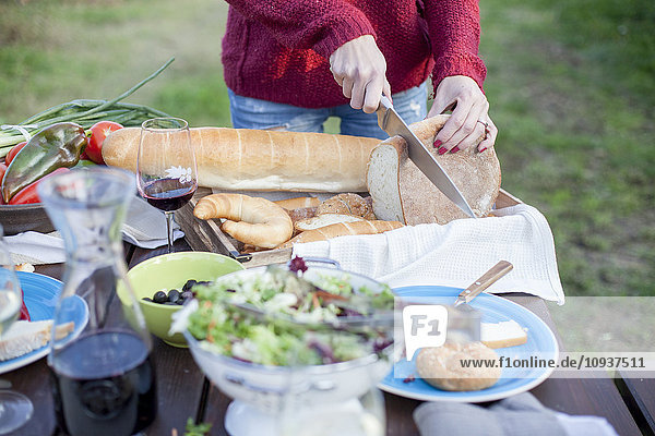 Person on garden party slicing loaf of bread