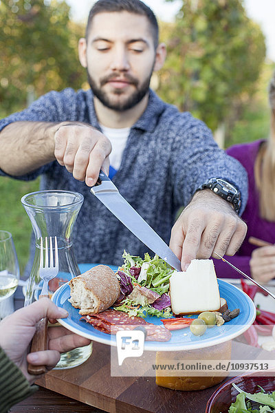 Man cutting cheese on garden party